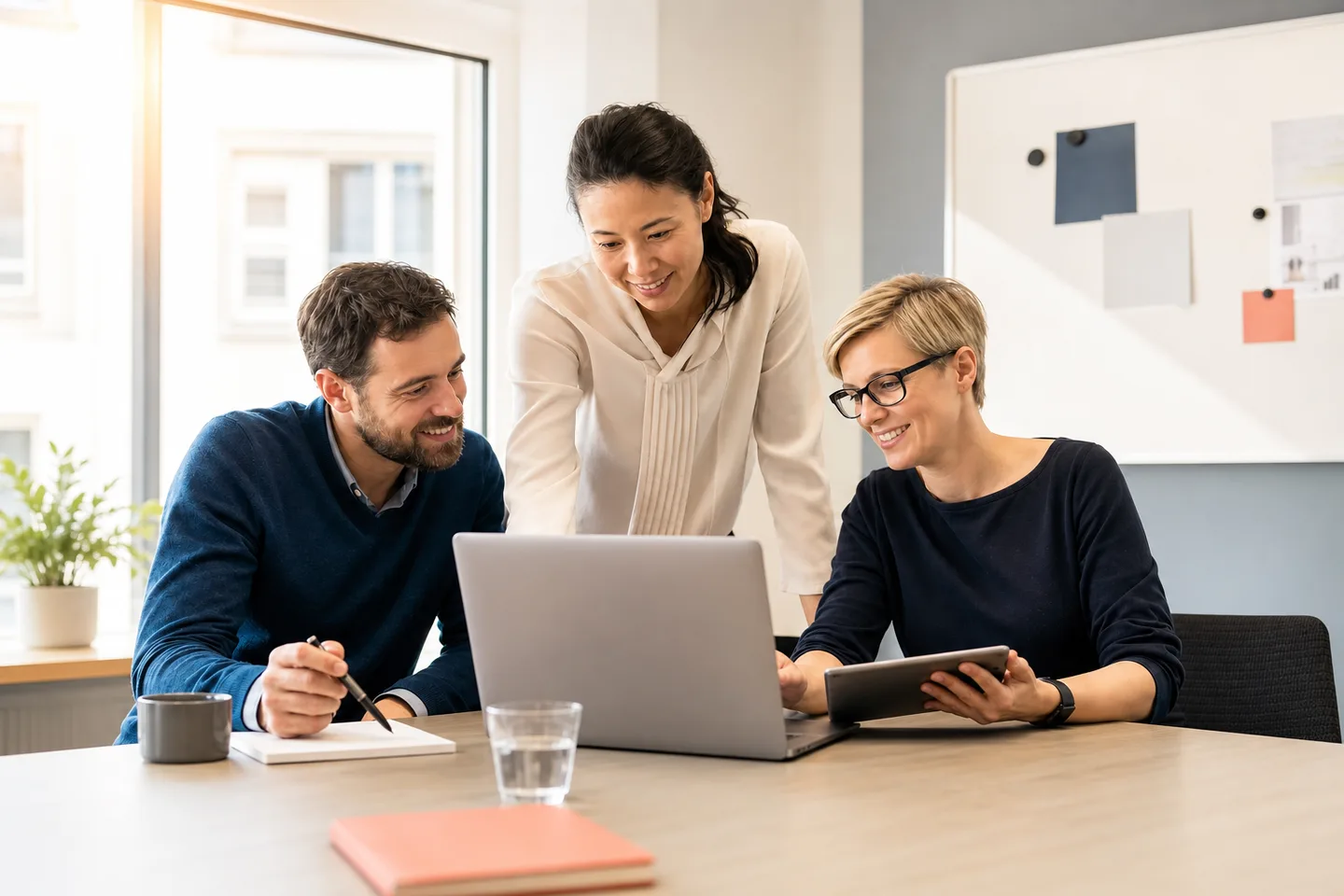 Drei Fachleute arbeiten freundlich und entspannt an einer digitalen Lernplattform